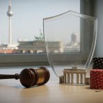 Stillleben: Richterhammer, Pokerchips und Spielkarten vor unscharfer Berliner Skyline mit Fernsehturm; kleines Brandenbu
